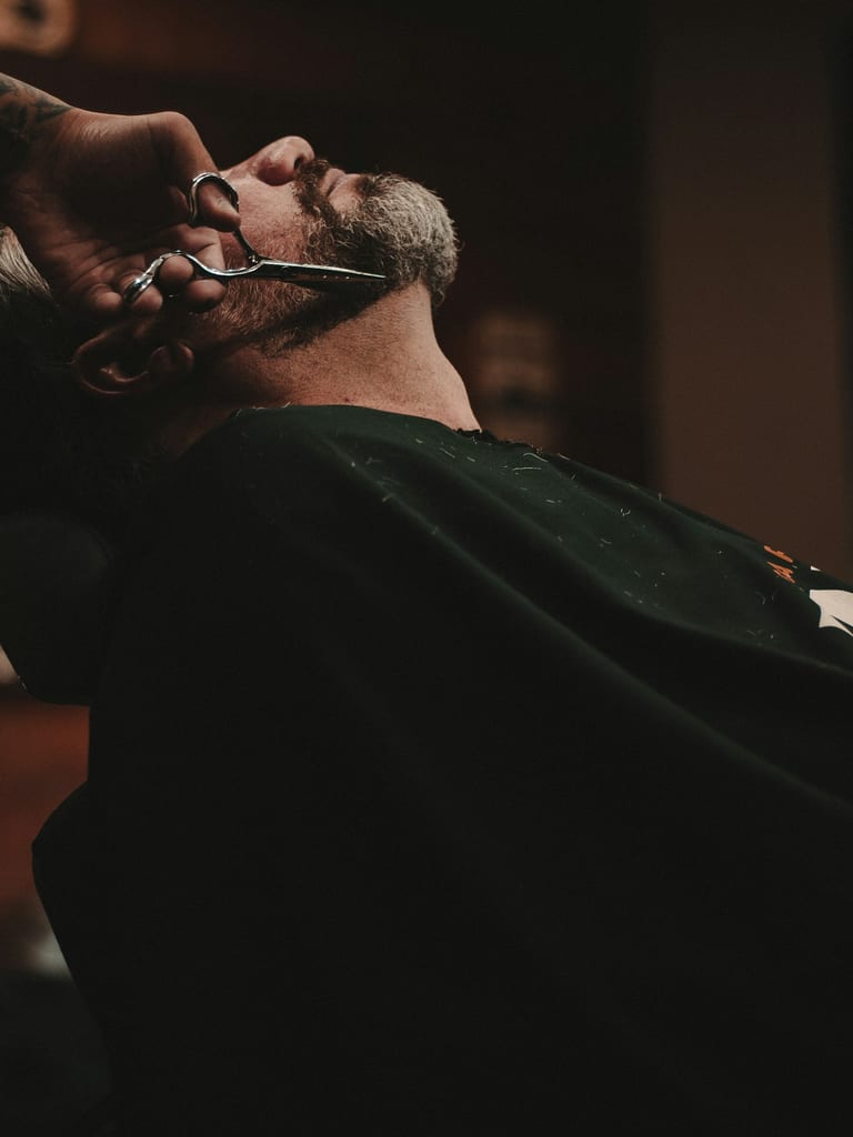 A barber finishing a beard trim with scissors