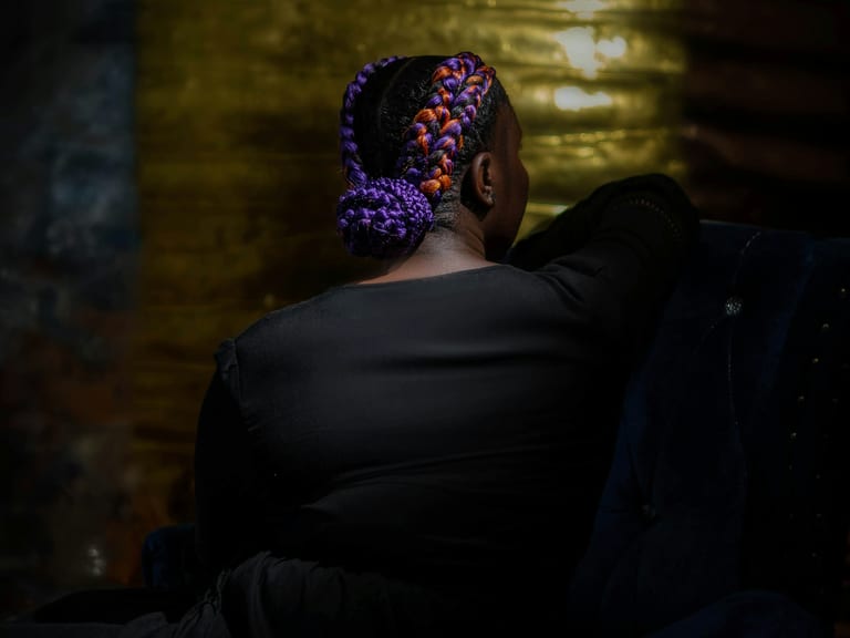 Braids gathered into an updo, lit from behind