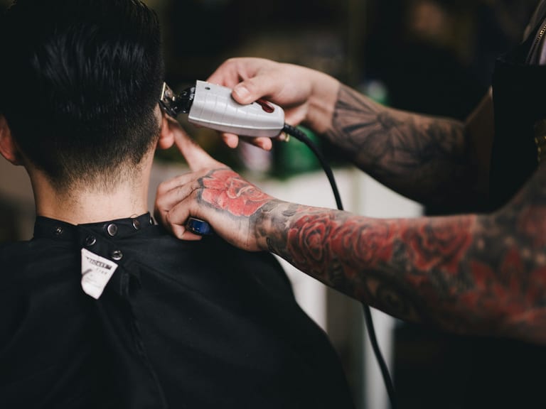 A barber cutting a clean line at the nape with clippers